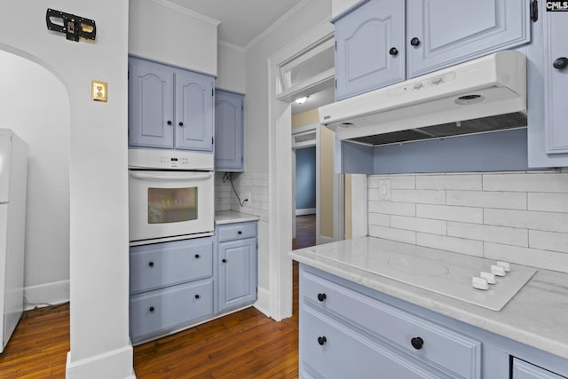 kitchen featuring under cabinet range hood, ornamental molding, dark wood finished floors, and white oven