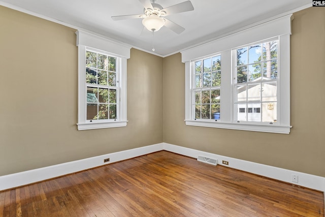 unfurnished room with ceiling fan, hardwood / wood-style flooring, visible vents, baseboards, and crown molding