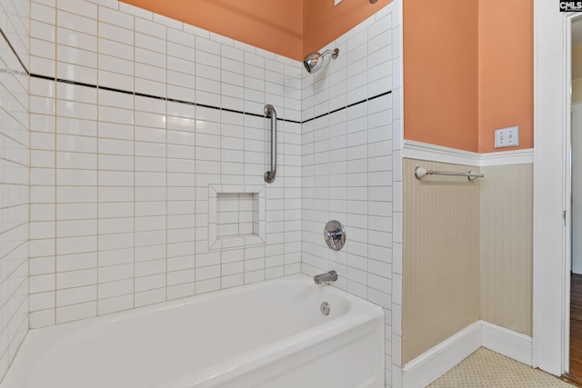 bathroom with a wainscoted wall and tub / shower combination