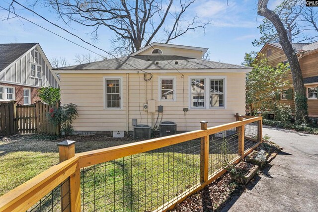 back of property with central AC unit, a lawn, and fence private yard