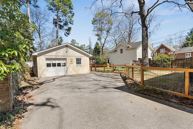 detached garage featuring fence and driveway