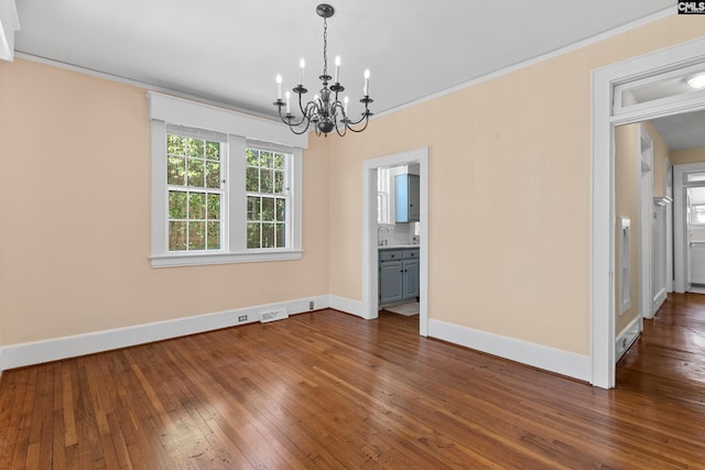 interior space with visible vents, baseboards, an inviting chandelier, dark wood finished floors, and crown molding