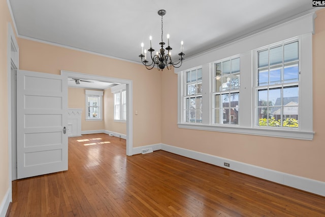 spare room with wood-type flooring, visible vents, an inviting chandelier, ornamental molding, and baseboards