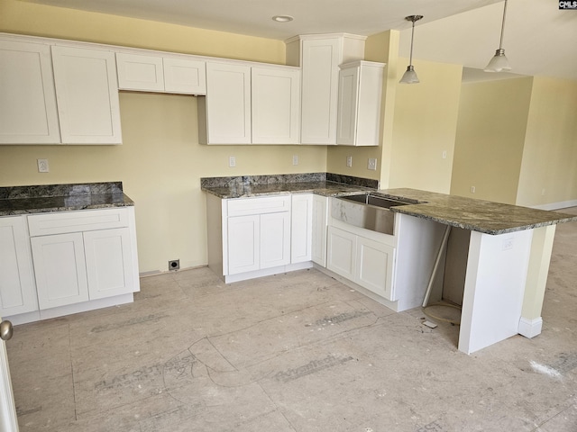 kitchen featuring dark stone counters, white cabinetry, and a peninsula