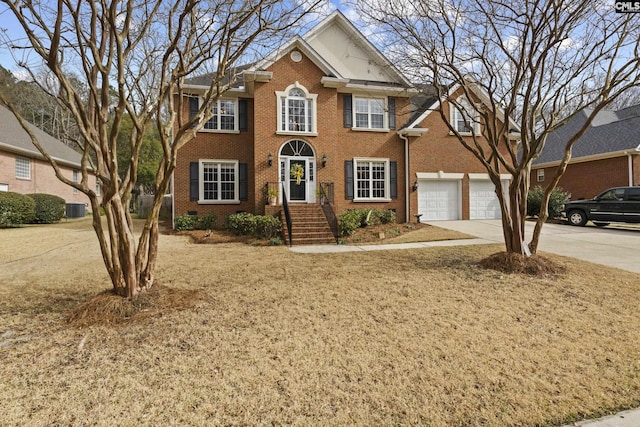 colonial inspired home with a garage, concrete driveway, crawl space, central AC, and brick siding