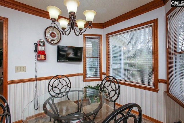 dining area with crown molding, wainscoting, a notable chandelier, and a textured ceiling