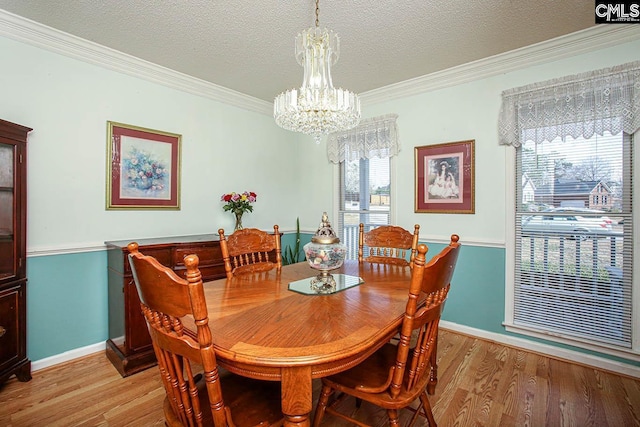 dining room with light wood finished floors, baseboards, ornamental molding, an inviting chandelier, and a textured ceiling