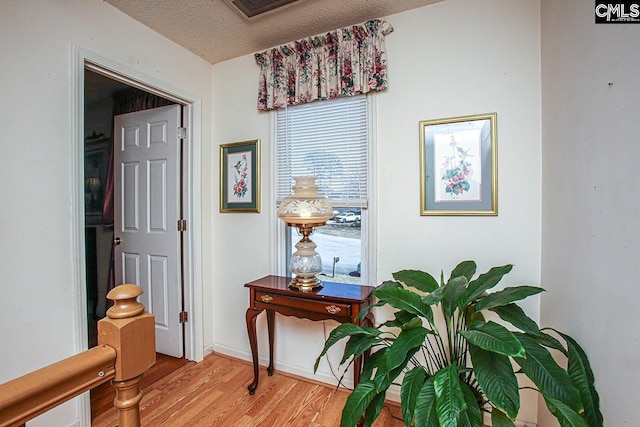 interior space with a textured ceiling, light wood-type flooring, and baseboards