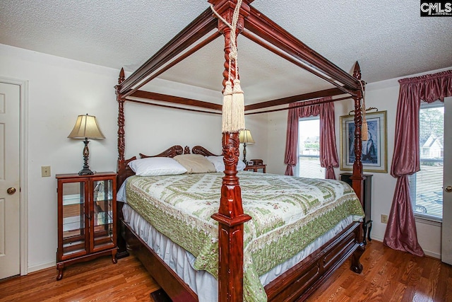 bedroom with a textured ceiling, access to outside, and wood finished floors