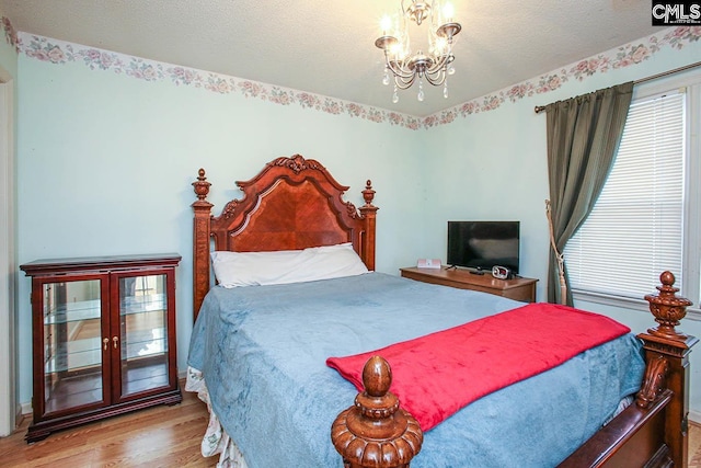 bedroom featuring a textured ceiling, a chandelier, and wood finished floors