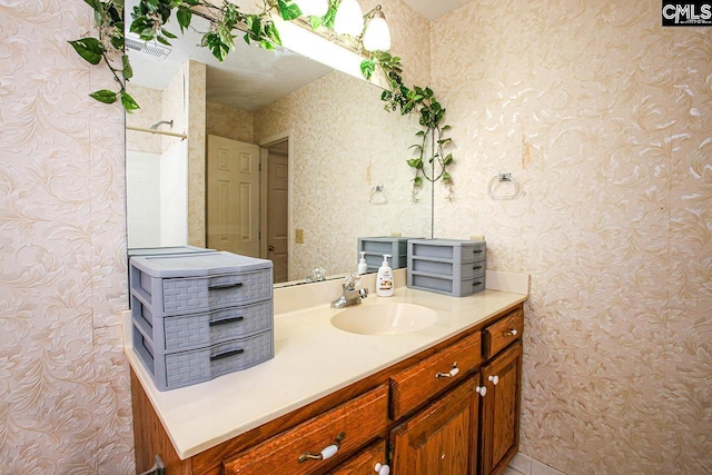 bathroom with wallpapered walls and vanity