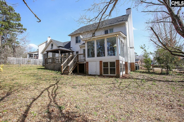 back of property with a deck, fence, a sunroom, stairway, and a chimney