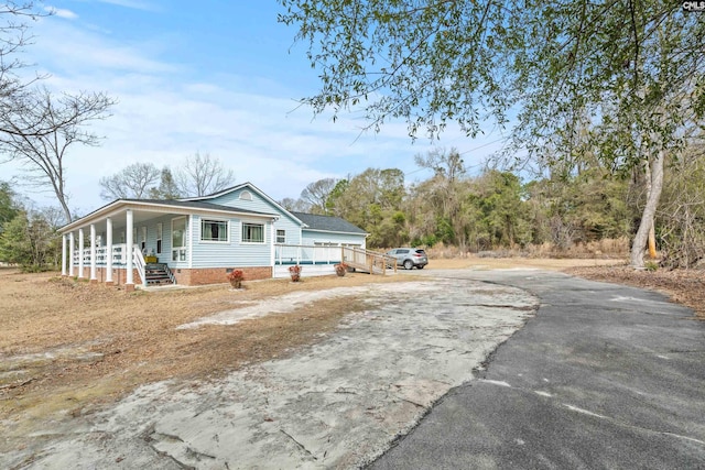 view of front of home featuring driveway, crawl space, and a porch