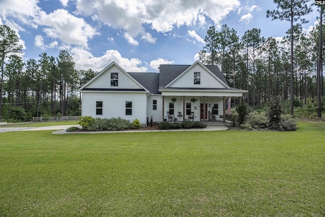 view of front of house with a porch, fence, a front lawn, and board and batten siding