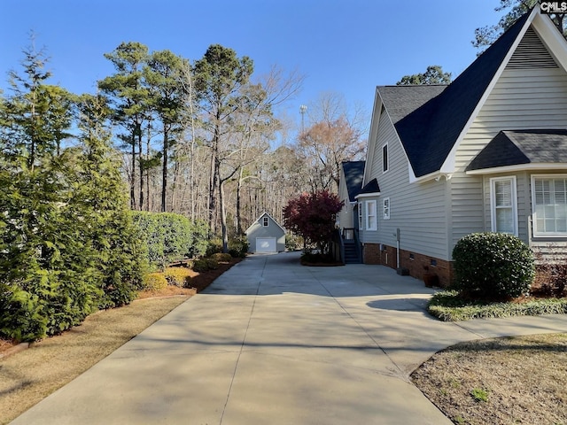 view of side of home featuring a shingled roof, an outbuilding, crawl space, and a detached garage