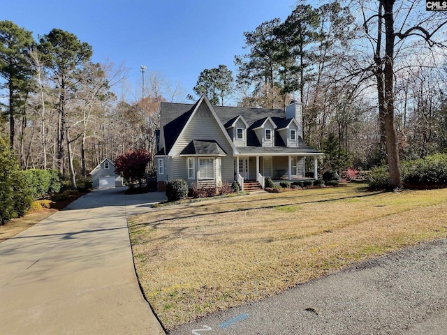 cape cod house with an outbuilding, covered porch, concrete driveway, a front lawn, and a chimney