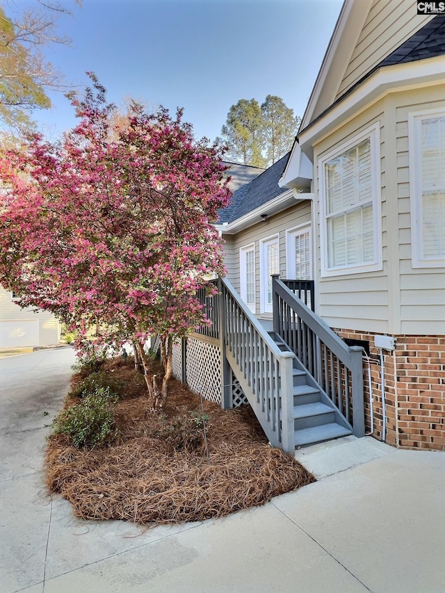 view of exterior entry featuring a shingled roof and a wooden deck