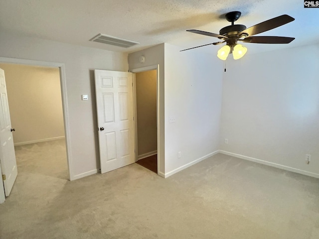 unfurnished bedroom featuring visible vents, baseboards, light colored carpet, ceiling fan, and a textured ceiling