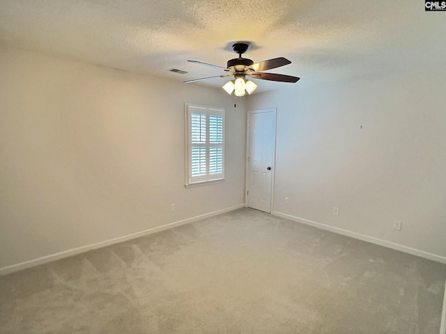 empty room with visible vents, baseboards, a textured ceiling, and light colored carpet