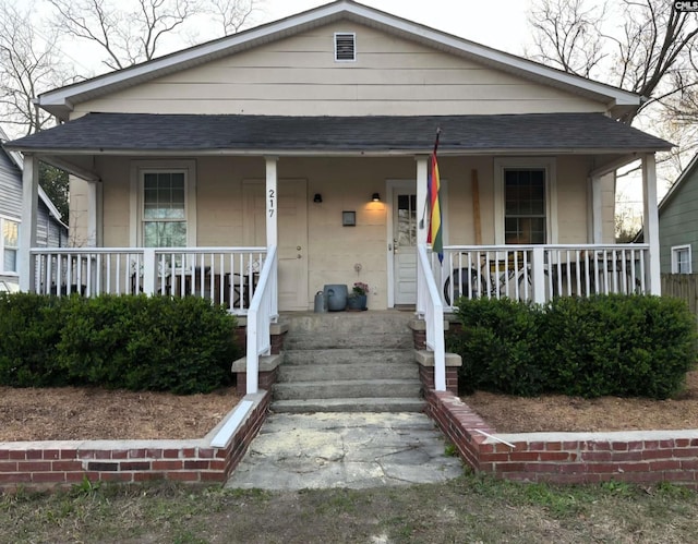 bungalow with a porch and roof with shingles