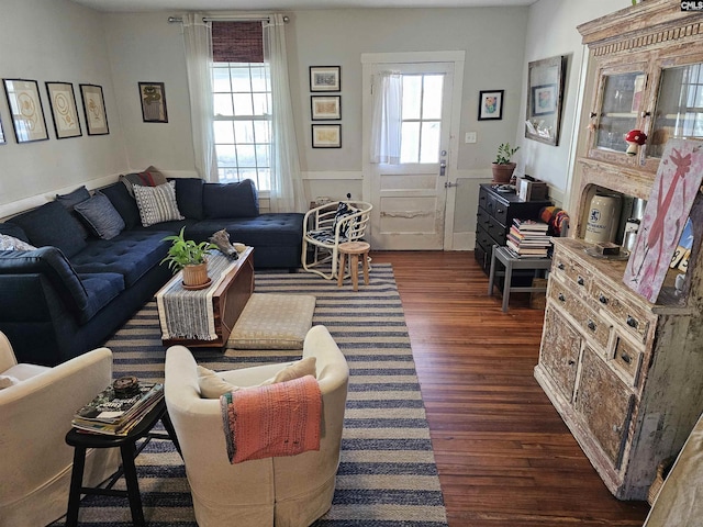 living room with a wainscoted wall and dark wood-style floors