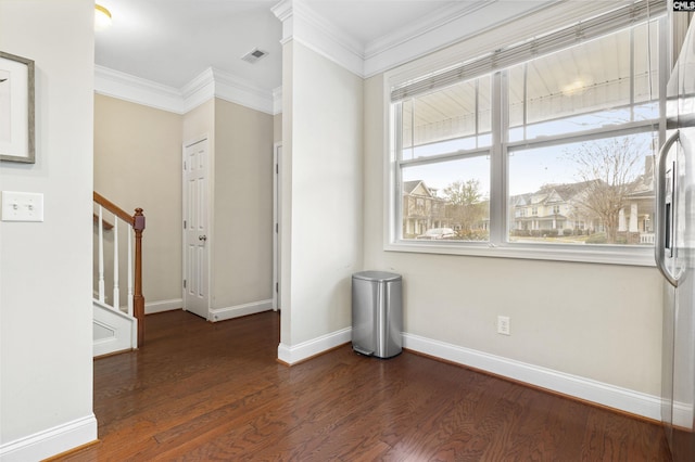 empty room with stairway, ornamental molding, visible vents, and wood finished floors