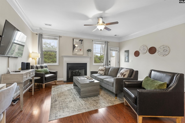 living area featuring visible vents, ornamental molding, a ceiling fan, hardwood / wood-style floors, and a fireplace