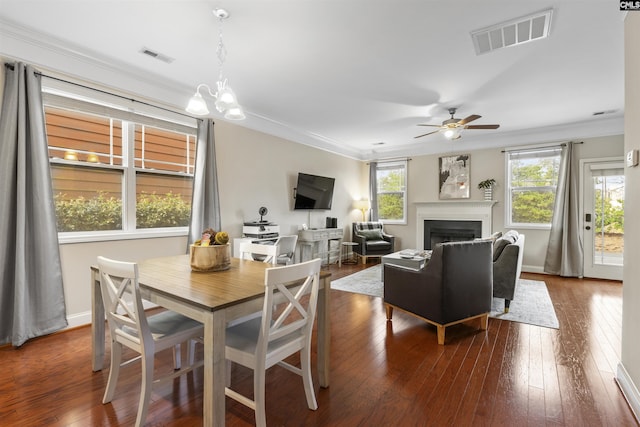 dining space with dark wood finished floors, crown molding, a fireplace, and visible vents