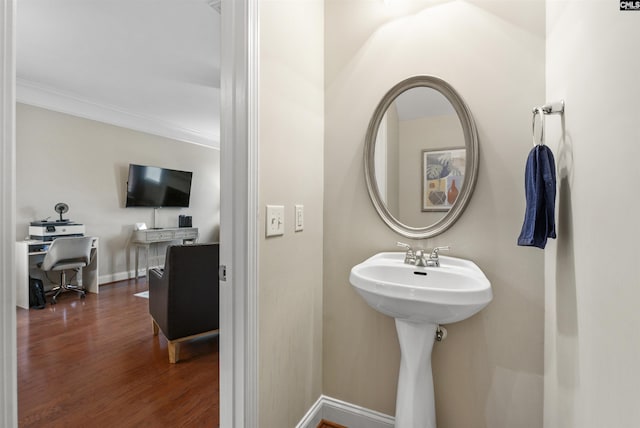 bathroom featuring crown molding, baseboards, and wood finished floors