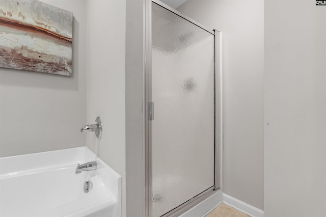 full bathroom featuring tile patterned flooring, a shower stall, a bath, and baseboards