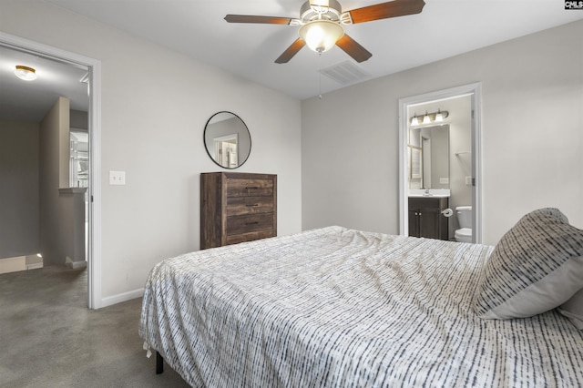 carpeted bedroom featuring a ceiling fan, baseboards, visible vents, ensuite bath, and a sink