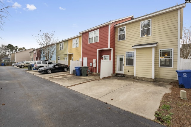 back of property with a residential view, uncovered parking, and fence