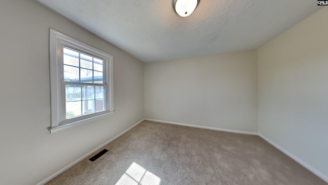 carpeted spare room featuring visible vents and baseboards