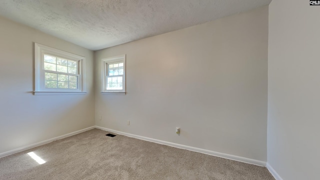 carpeted empty room featuring visible vents, baseboards, and a textured ceiling