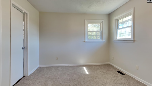 carpeted spare room with visible vents and baseboards