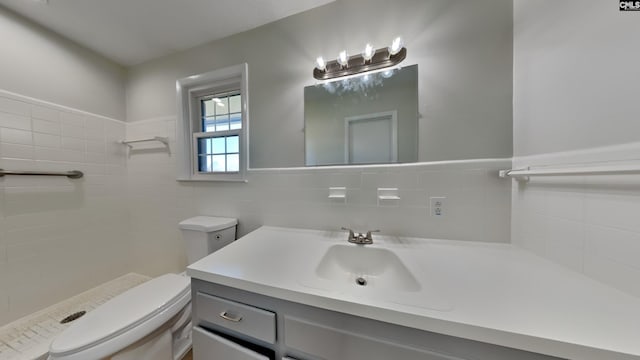 bathroom with toilet, tiled shower, tile walls, and vanity