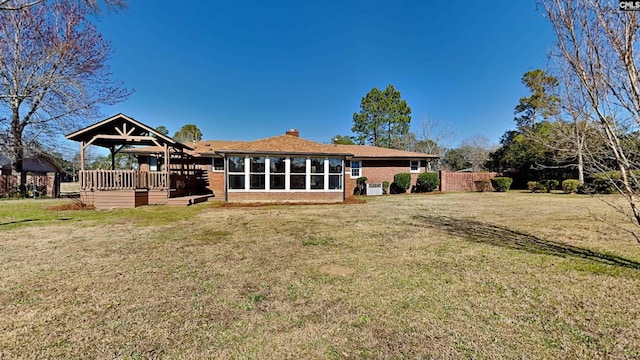 rear view of property with a gazebo, a lawn, and brick siding