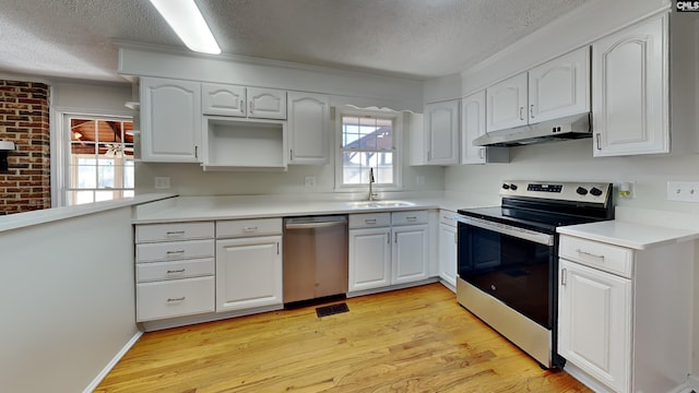 kitchen with white cabinets, stainless steel appliances, light wood-type flooring, under cabinet range hood, and a sink