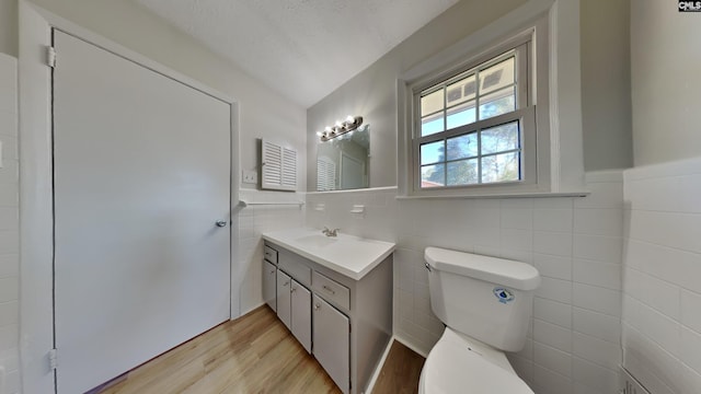 half bath with wainscoting, vanity, toilet, and wood finished floors