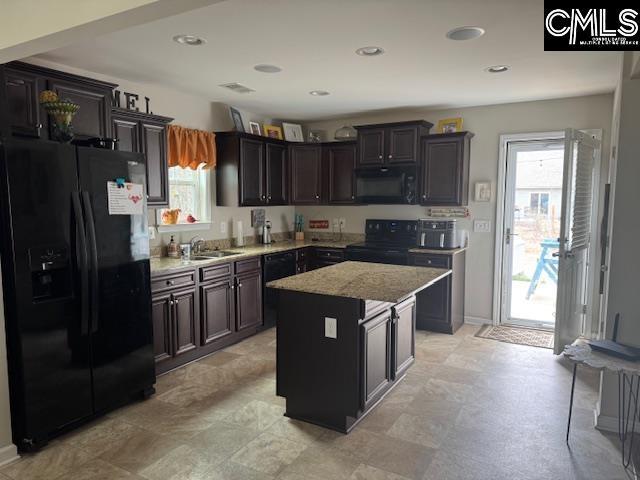 kitchen featuring a center island, recessed lighting, a sink, light stone countertops, and black appliances