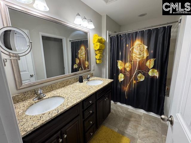 full bathroom featuring double vanity and a sink