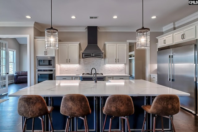 kitchen with a center island with sink, tasteful backsplash, custom range hood, white cabinets, and built in appliances