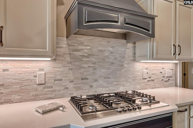 kitchen featuring stainless steel gas cooktop, light countertops, tasteful backsplash, and custom range hood