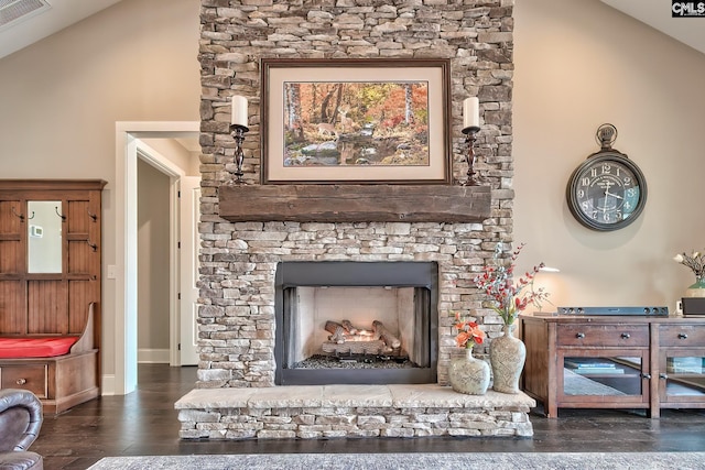 room details featuring a fireplace with raised hearth, visible vents, baseboards, and wood finished floors