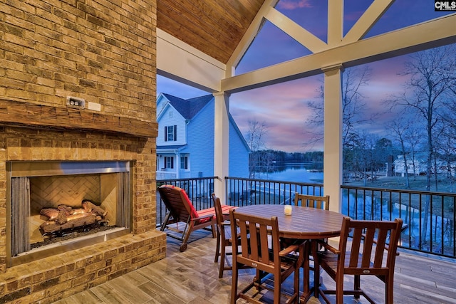 sunroom / solarium featuring vaulted ceiling, an outdoor brick fireplace, and wooden ceiling