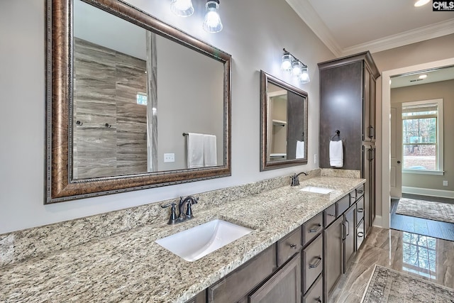 full bathroom featuring double vanity, crown molding, baseboards, and a sink