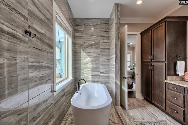 full bathroom with a soaking tub, ornamental molding, and tile walls