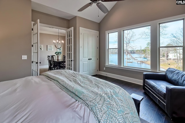 bedroom with dark wood finished floors, a water view, vaulted ceiling, baseboards, and ceiling fan with notable chandelier