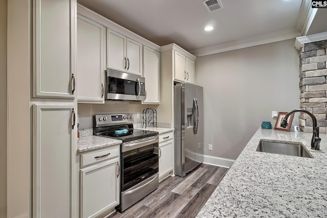 kitchen with dark wood-style flooring, crown molding, stainless steel appliances, visible vents, and a sink