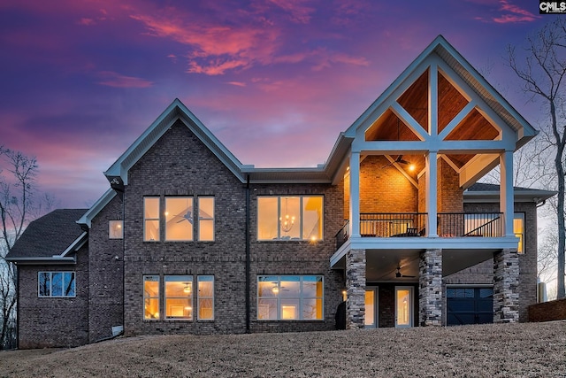 back of property at dusk with a balcony and brick siding